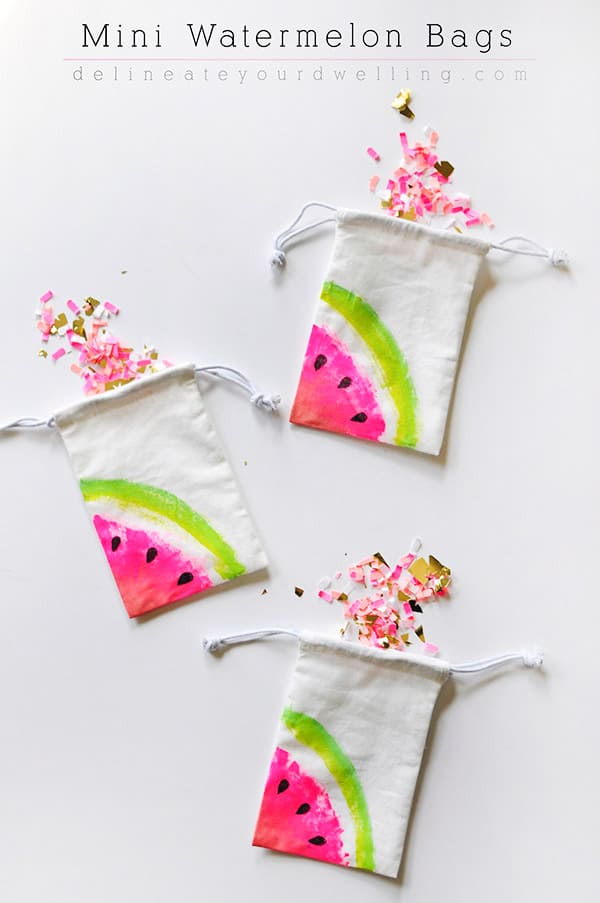 Small drawstrings bags painted with watermelon wedges on the corner and pink confetti spilling from the bags