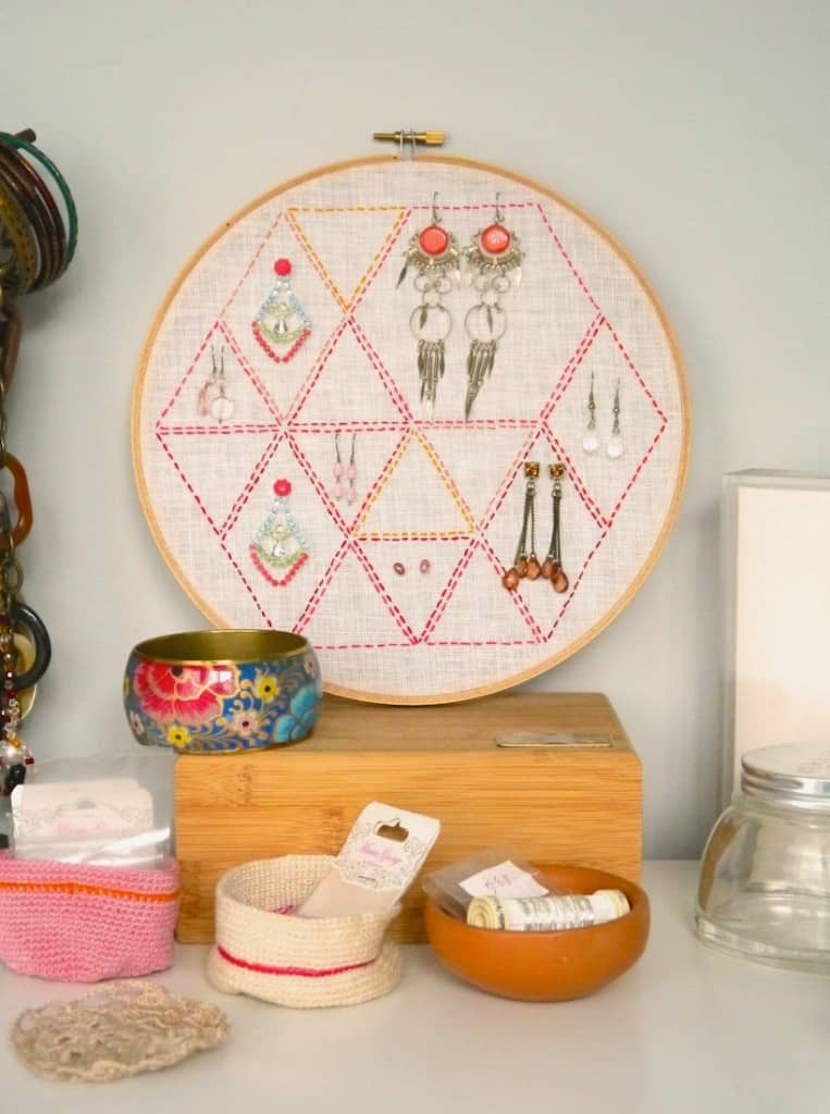 Embroidery hoop wth hexagon pattern and various earrings attached to it