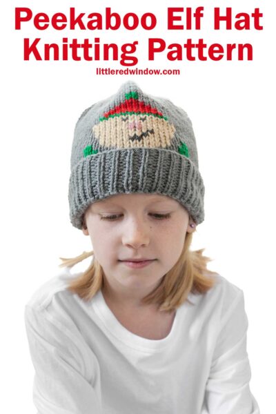 Child wearing a gray knit hat featuring an adorable elf design. Text above reads, "Peekaboo Elf Hat Knitting Pattern," sourced from "littleredwindow.com." Ideal for those seeking a charming elf hat knitting pattern.