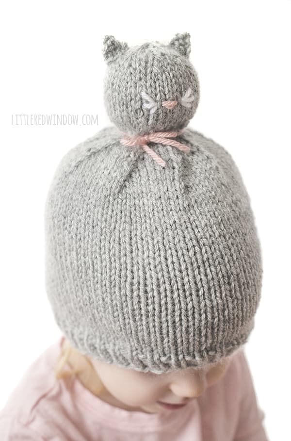 The Kitty Cat Pom Pom Pet Hat knitting pattern has a sweet embroidered pink nose and adorable little whiskers!