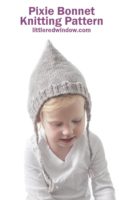 small toddler in white shirt wearing tan pointed knit pixie bonnet with braided ties and looking down