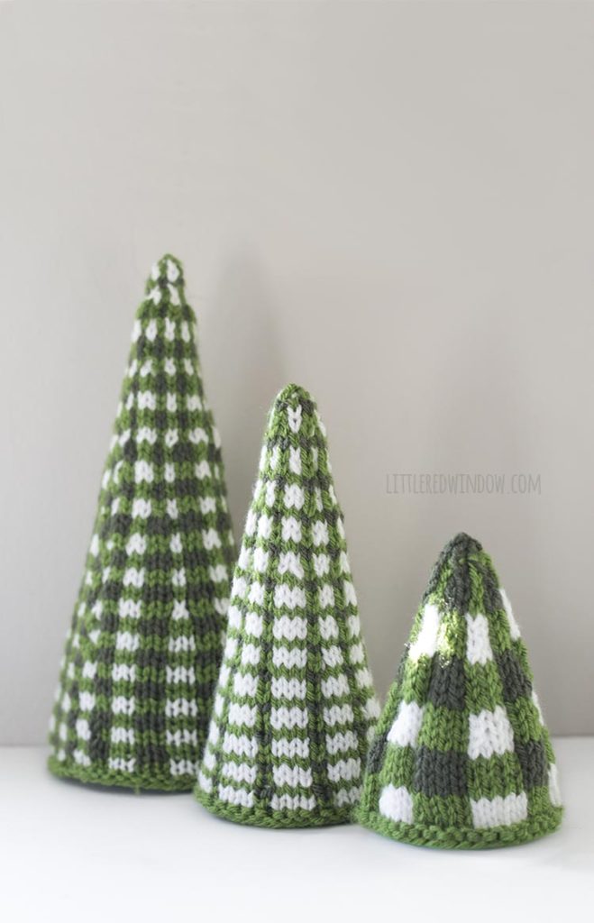 Three green and white plaid knit Christmas tree shapes in a line from large to small