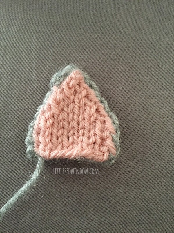 Assembled gray and pink knit cat ear sitting on a gray background