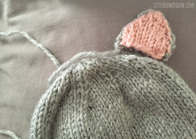 Image showing were to place the assembled cat ear on top of the gray knit cat hat