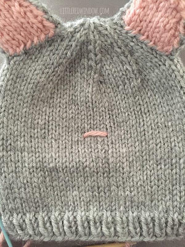 Image showing first horizontal stitch in pink yarn on the front of the cat hat