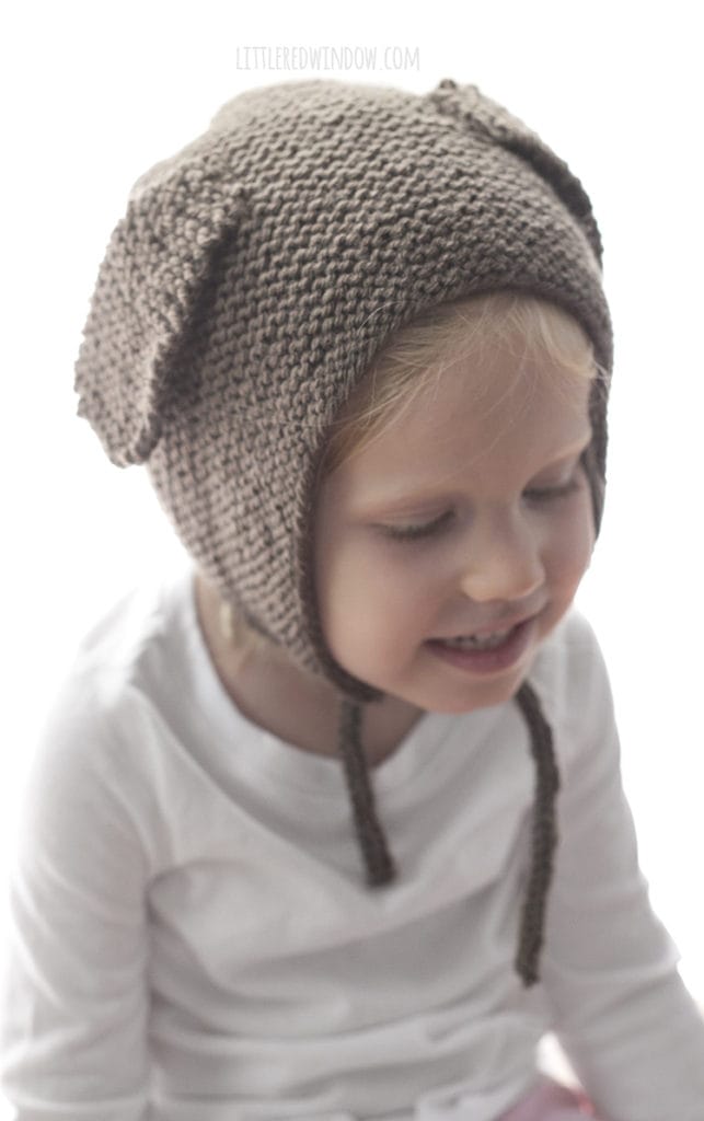 Little girl wearing brown knit bonnet with floppy puppy ears on the sides