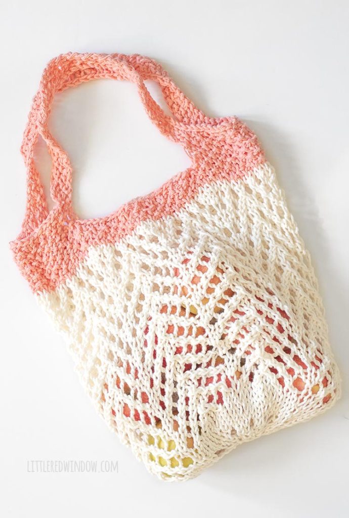 cream and coral chevron lace knit market bag filled with apples laying flat on a white floor