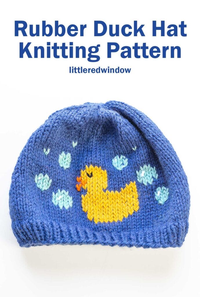 Blue knitted hat with a yellow rubber duck and light blue bubbles design. Text above reads: