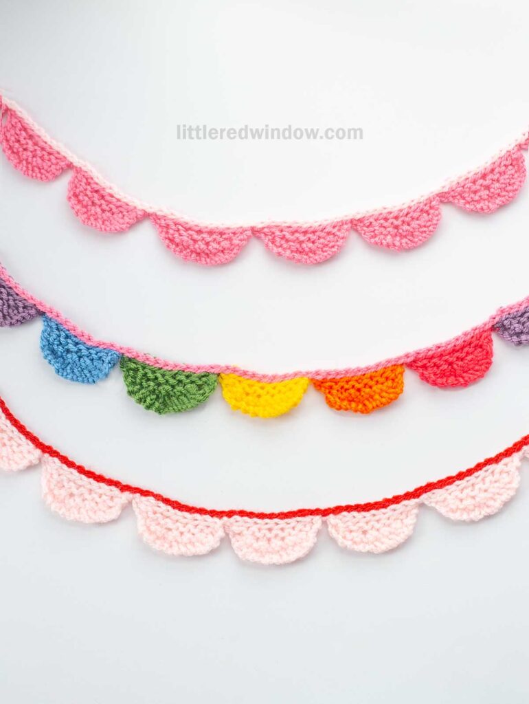Three crochet scalloped garlands in various colors, including pink, purple, blue, green, yellow, and orange, are displayed horizontally on a white background. The garlands have a whimsical, colorful appearance.