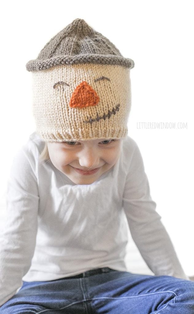 little girl laughing and wearing a scarecrow hat