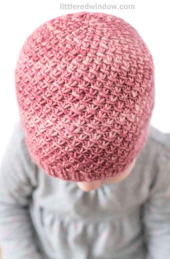 top view of knit slip knit twist hat in a medium pink hand dyed malabrigo yarn in front of a white background