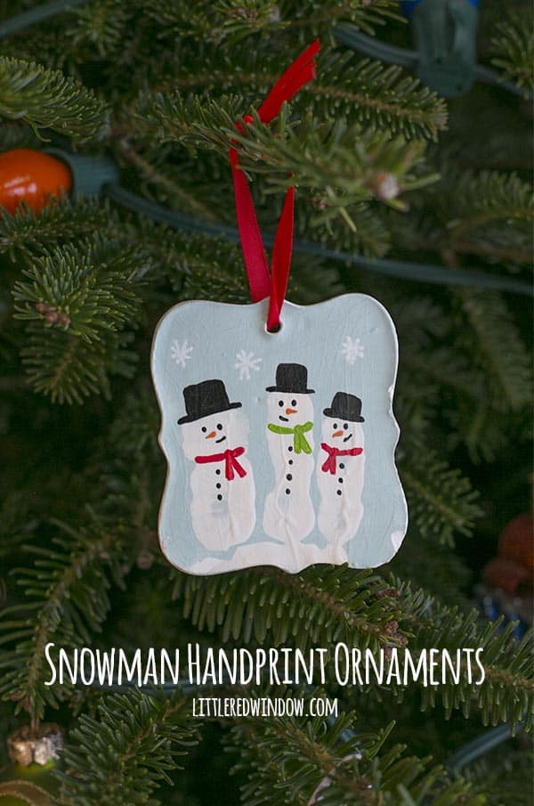 finished ornament hanging on a Christmas tree, this side has three fingerprint snowmen wearing black hats