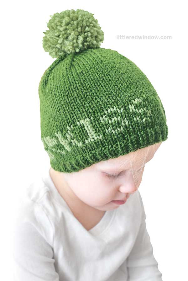 A child sports a green knit St. Patrick's Day hat with a pom-pom and