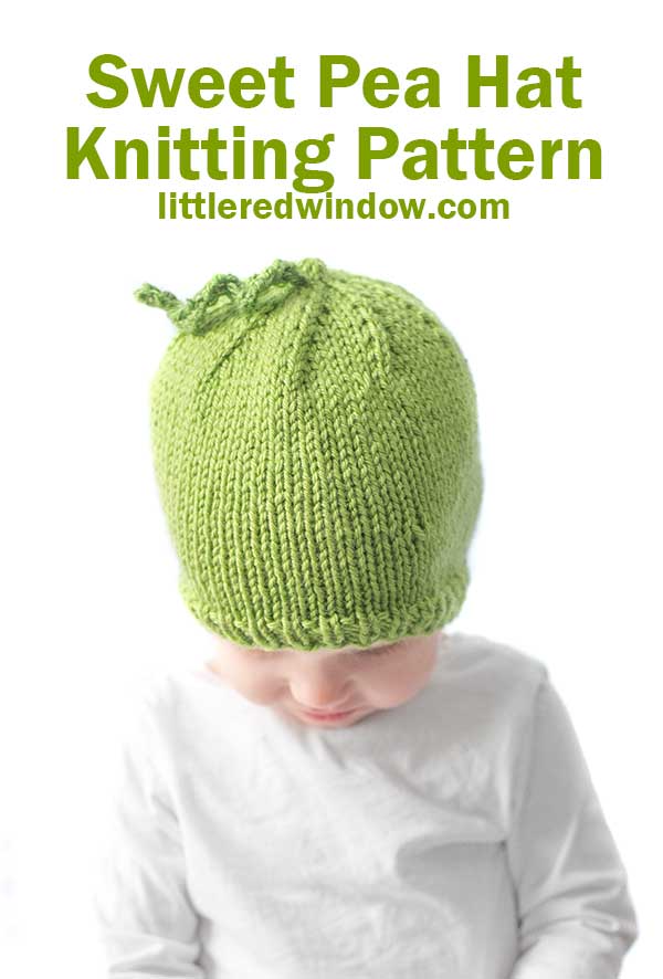 baby in white shirt wearing a bright green knit hat with curly tendril on top that looks like a sweet pea looking down at their lap