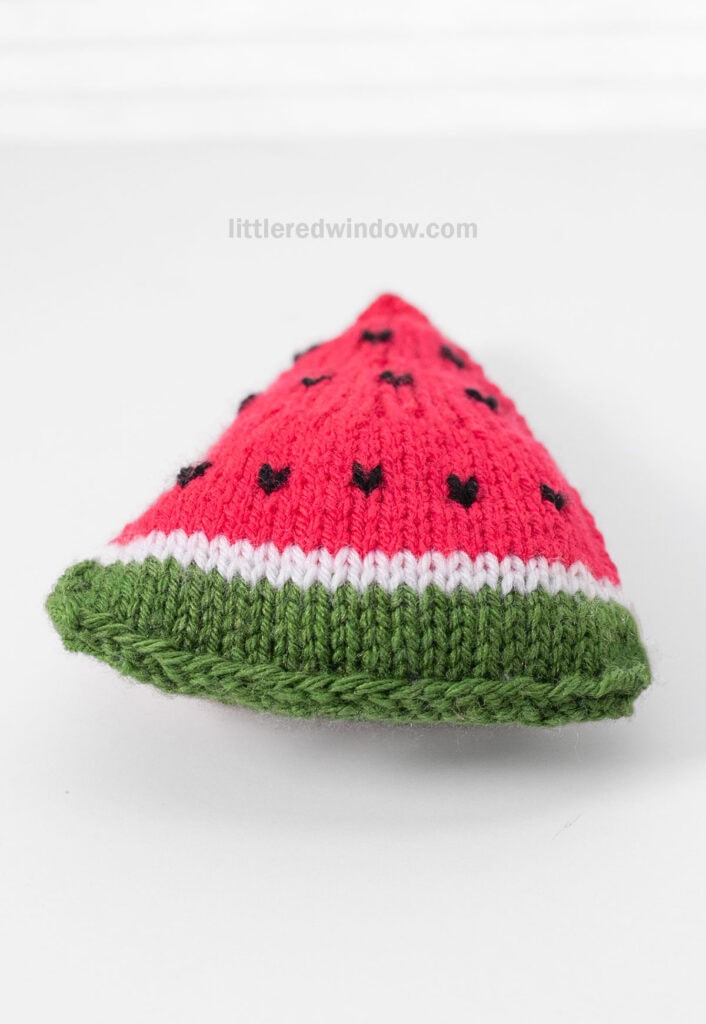 view from the side of rind side of a knit watermelon slice on a whitbackground