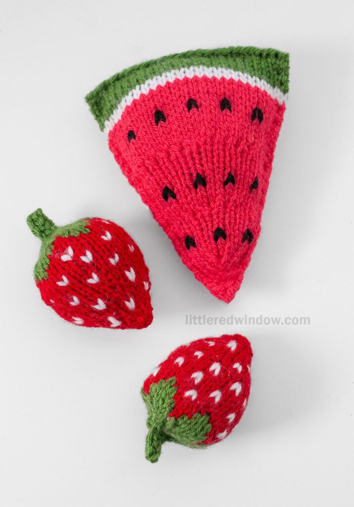 knit watermelon slice and two knit strawberries on a white background