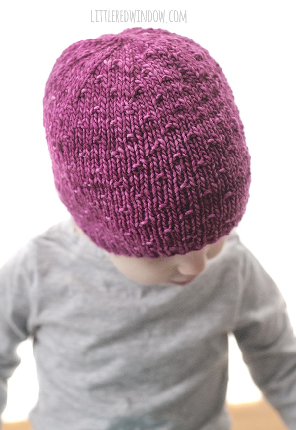 Girl wearing pink hat with polka dot texture and looking down