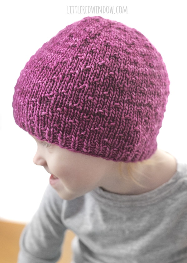 girl looking to the left and wearing pink knit dot hat