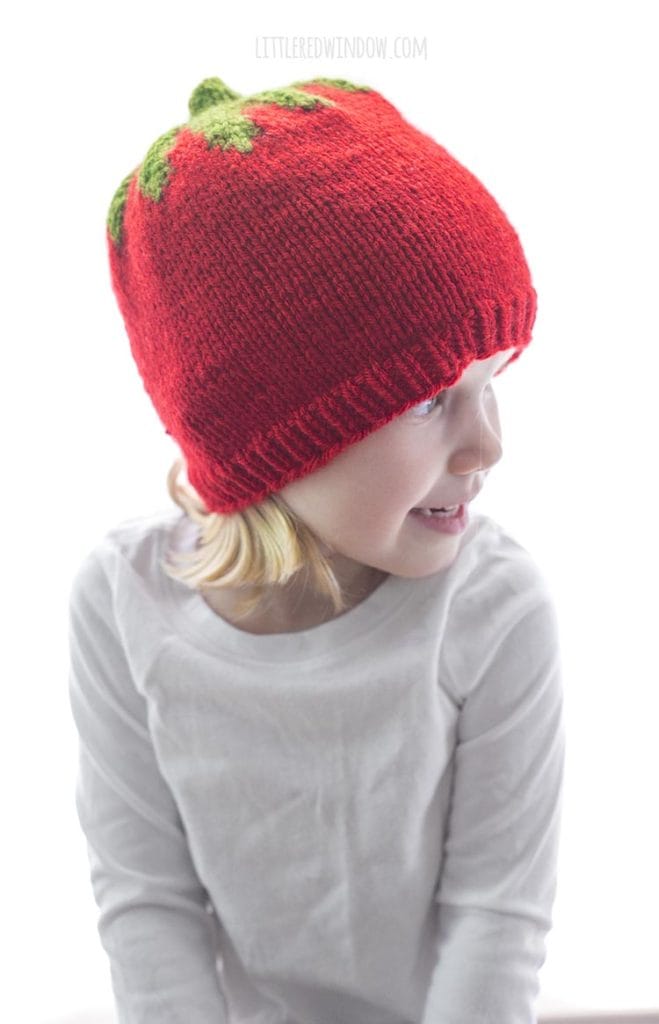 little girl wearing red knit tomato hat and looking to the right