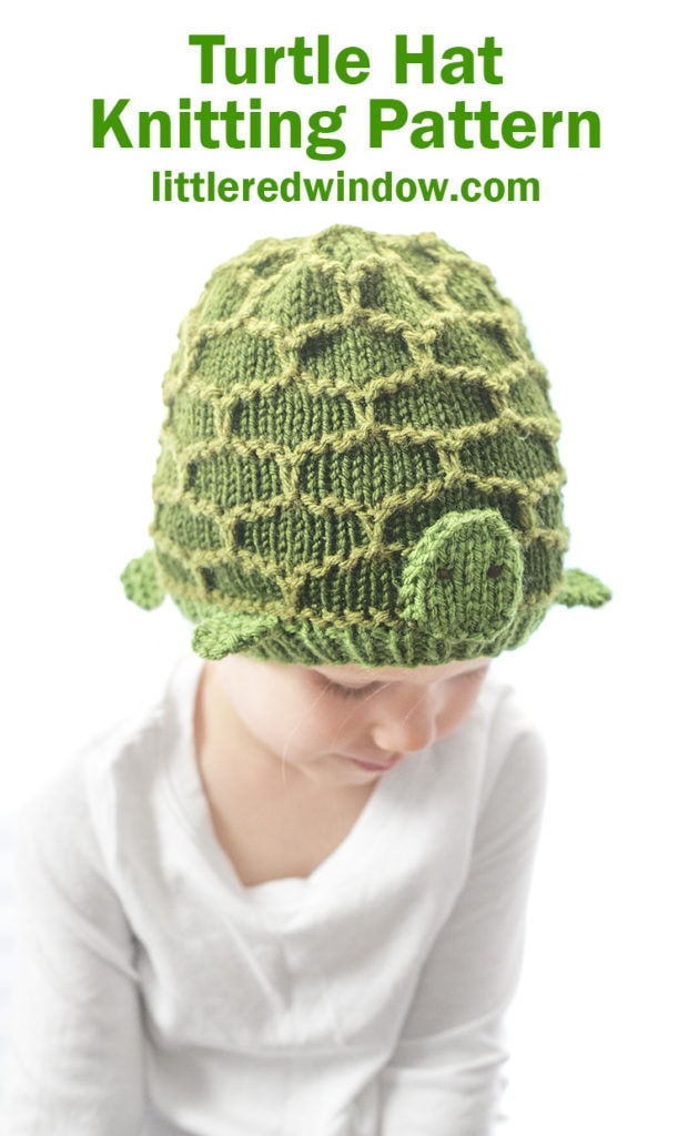 little girl looking down and wearing a green turtle hat