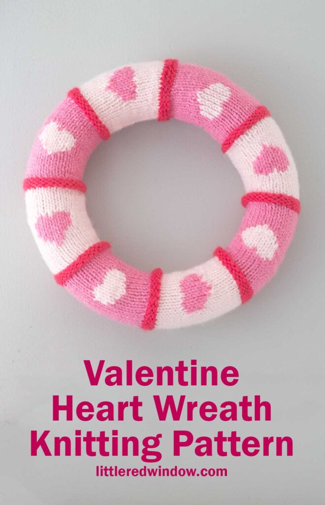 A knitted wreath with pink and white stripes and heart patterns. The caption reads