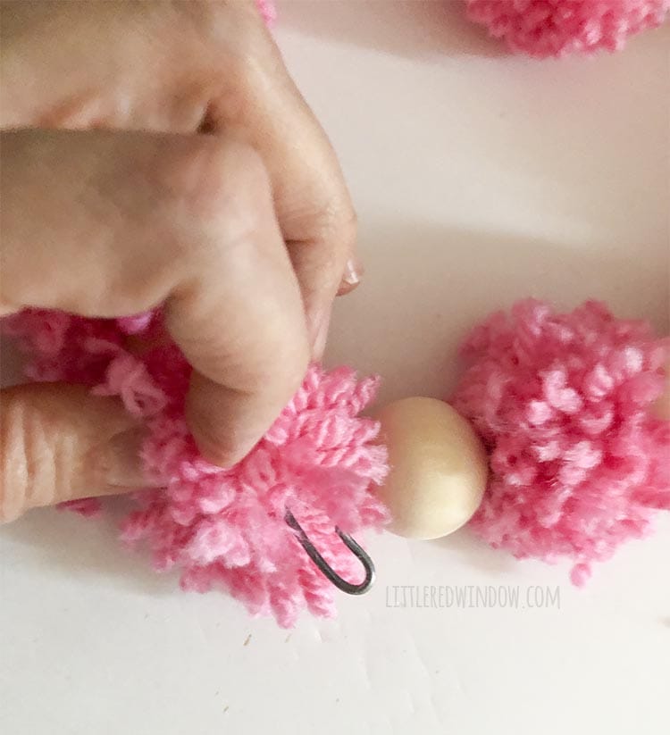 hand showing other end of wire bent into a U shape to hook into the other wire end to connect the bottom of the heart shape