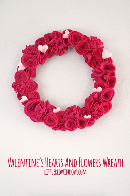 Wreath with hot pink felt flowers and light pink hearts hanging on a wall