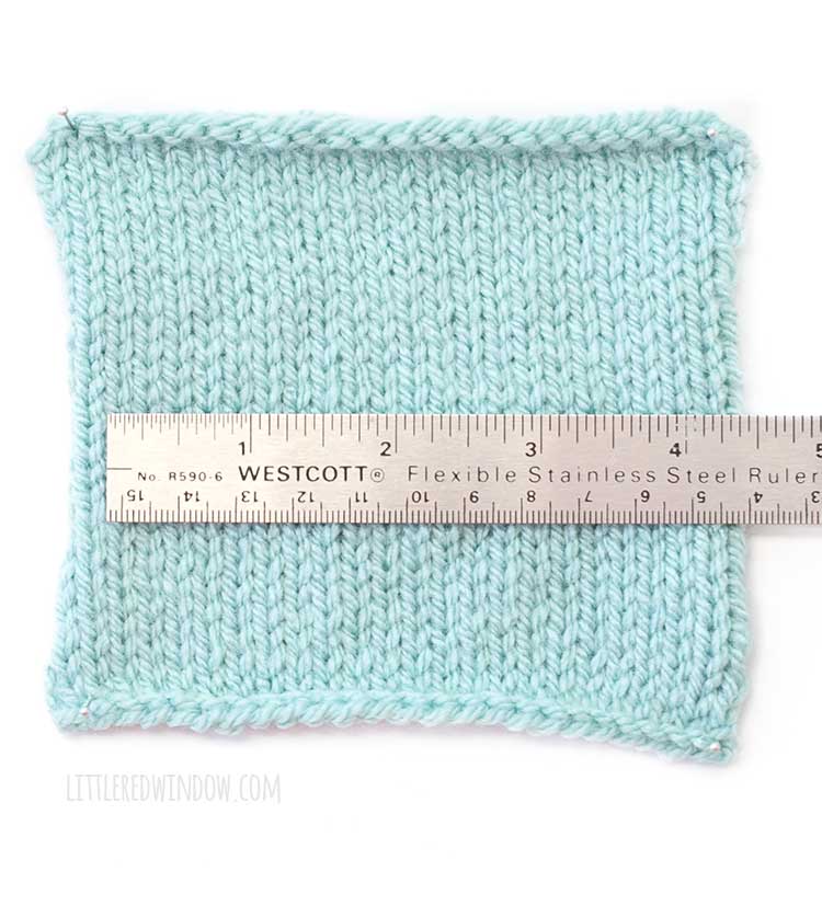 a square of light blue stockinette stitch knitting with a 6 inch steel ruler on top so you can measure the gauge