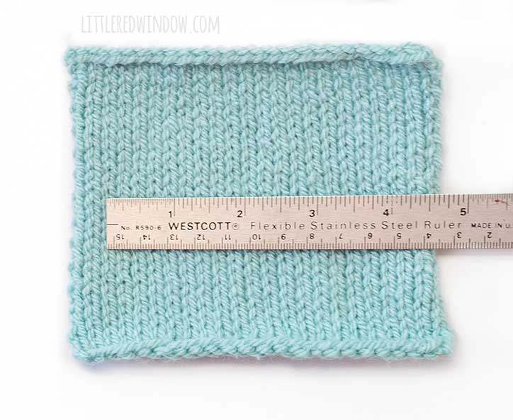 a square of light blue stockinette stitch knitting with a 6 inch steel ruler on top so you can measure the gauge