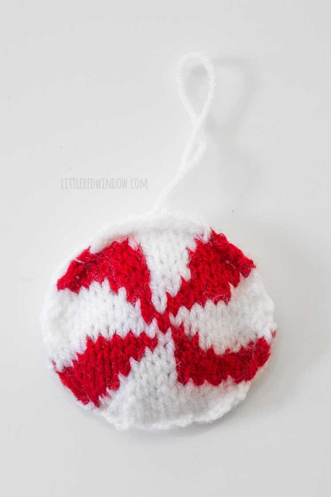 closeup of round knit red and white peppermint candy Christmas tree ornament