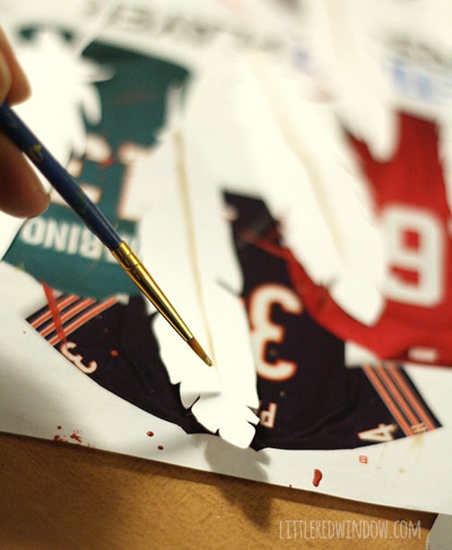 paintbrush painting gold details on white paper feather